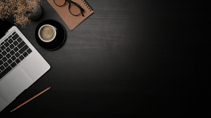 Mock up computer laptop, coffee cup and notebook on black table.