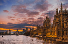 Beautiful View Of Parliament Buildings, Big Ben, And Other Buildings Of City Of Westminster At Sunset , In London, England; Buildings And Clouds Reflect In River Thames