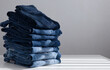 a pile of blue jeans on a light background. Close up. Copy space