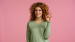 happy redhead woman in green jumper showing okay gesture isolated on pink