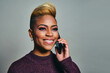 © Carlos David - Smiling young woman looking away while using smart phone against gray background