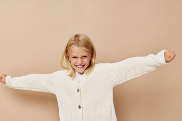 Wall Mural - Beautiful little girl gestures with his hands on a beige background