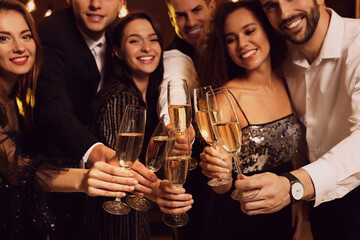 Wall Mural - Happy friends celebrating New Year indoors, focus on hands with glasses of sparkling wine