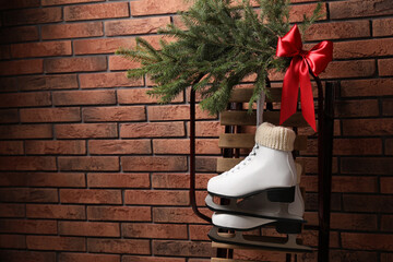 Sticker - Sleigh with pair of ice skates and fir branches near brick wall, space for text