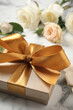 Golden gift box and beautiful roses on white marble table, closeup