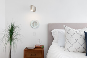 A bedroom detail shot with a light mounted on the wall over the bedside table.