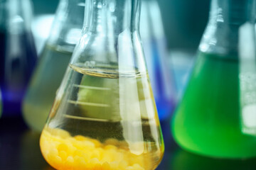 Wall Mural - orange and green solution in science glass flask at chemistry lab background