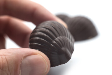 Wall Mural - Closeup of pralines chocolates in hand on white background