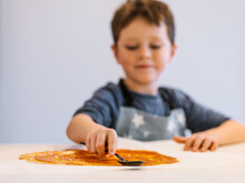 Boy Spreading Sauce On Pizza Dough