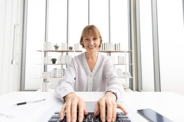 Wall Mural - senior woman typing keyboard on laptop computer, talking and looking to someone from chat online