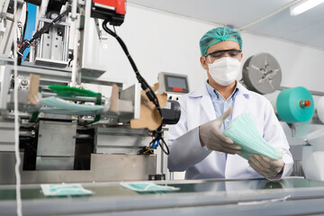 Wall Mural - male factory worker are producing medical face masks, counting and checking of quality from machine