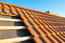 Overlapping Rows Of Yellow Ceramic Roofing Tiles Mounted On Wooden Boards Covering Residential Building Roof Under Construction