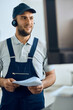 © Drazen - Happy mechanic with headset uses computer while working at auto repair shop.