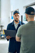 © Drazen - Foreman of auto repair shop uses laptop and talks to a mechanic in workshop.