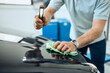 © Drazen - Close-up of mechanic uses lamp while examining hood of a car.