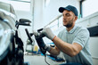 © Drazen - Young worker polishes car while working in auto repair shop.