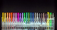 A Set Of Multi-colored Helium Pens In A Plastic Package Close-up On A Black Background