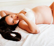 © iordani - young pretty woman at home pregnant laying on bed in lingerie, lifestyle people concept