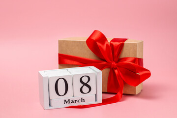 Gift in a craft box with a red bow and a calendar with the date of March 8th.