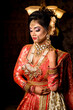 Portrait of very beautiful young Indian bride in luxurious bridal costume with makeup and heavy jewellery in studio lighting indoor. Wedding Fashion and Lifestyle.