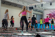 Mini Rebounder Workout: People doing Fitness Exercise in Class at Gym with Music and Teacher on Stage