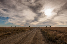 A Horizontal Shot Of A Rural Dirt Road In Bisecting Two Farms, Against A Backdrop Of A Dramatic, Sormy, Cloudy Sky At Susnet, Bloemfontein, Free State, South Africa