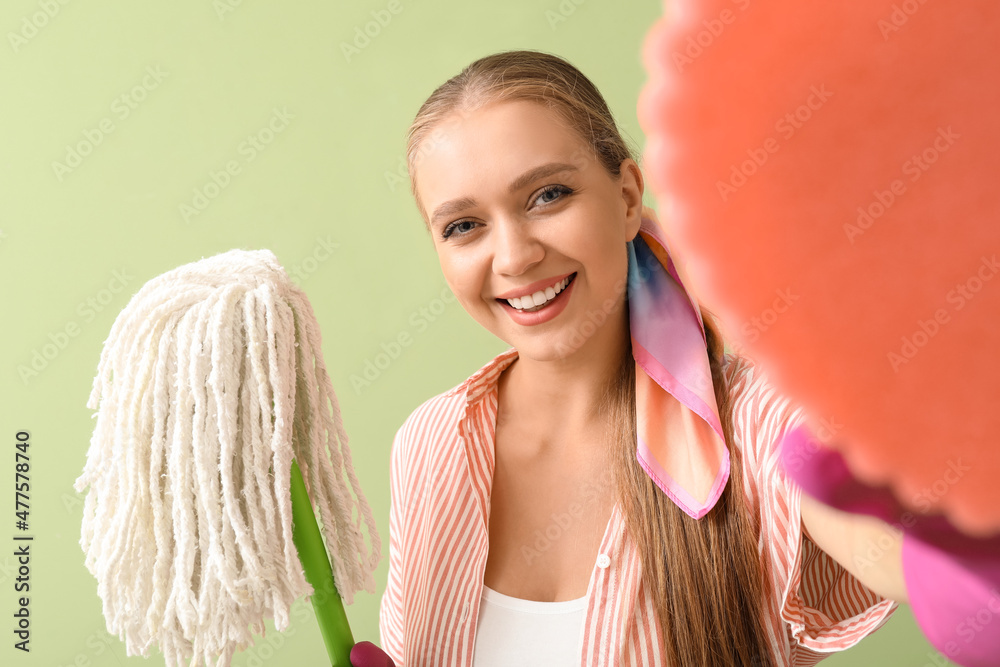 Young woman with sponge and floor mop on color background