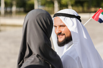 Wall Mural - Couple in traditional clothes and with the national flag of UAE outdoors