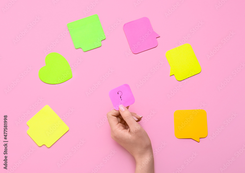 Woman holding sticky note with question mark on pink background