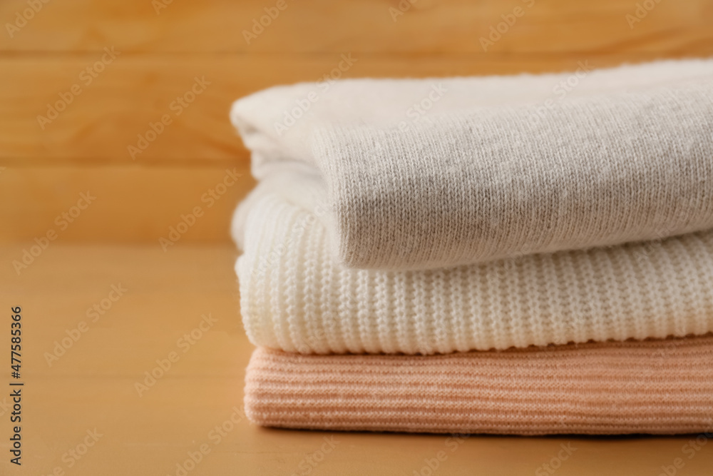 Stack of different cozy sweaters on wooden background