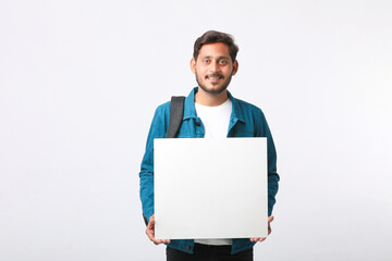 Canvas Print - Young indian college student showing blank sign board on white background.