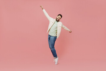 Wall Mural - Full body young smiling happy man 20s wearing trendy jacket shirt leaning back, dance stand on toes have fun isolated on plain pastel light pink background studio portrait. People lifestyle concept.