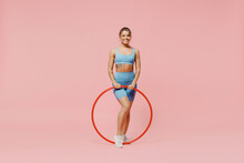 Full Size Young Strong Sporty Athletic Fitness Trainer Instructor Woman Wear Blue Tracksuit Spend Time In Home Gym Use Hula Hoop Isolated On Pastel Plain Light Pink Background. Workout Sport Concept.