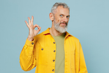 Wall Mural - Elderly satisfied caucasian fun gray-haired mustache bearded man 50s wear yellow shirt showing okay ok gesture isolated on plain pastel light blue background studio portrait. People lifestyle concept.