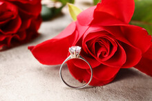 Silver Engagement Ring And Beautiful Red Rose On Grunge Background, Closeup