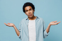 Puzzled Bemused Young Black Curly Man 20s Years Old Wear White Shirt Spreading Hands Shrugging Shoulders Standing Questioned And Unaware Isolated On Plain Pastel Light Blue Background Studio Portrait