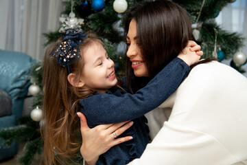 Beautiful young mother with her daughter near the Christmas tree. Christmas. New Year.