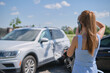 © bilanol - Stressed driver talking on sellphone on roadside near her smashed vehicle calling for emergency service help after car accident. Road safety and insurance concept