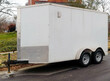 White  utility cargo trailer parked on residential city street.