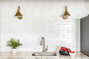 Kitchen Faucet with Light Brown Marble Countertop, White Subway Tile Backsplash and Gold Light Fixtures