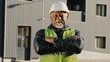 Close-up elderly african american man construction worker standing in protective helmet uniform outdoors confident workman crossed arms across chest successful builder contractor looking camera posing