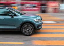 The Car Drives Quickly Through A Pedestrian Crossing, The Background Contains Motion Blur
