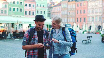 Couple of tourists using smartphone and admiring beautiful surroundings. They going sightseeing early in the morning.