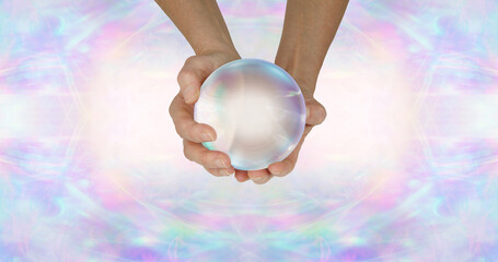 Wall Mural - Fortune Teller's crystal ball header background - female holding large clear scrying ball against a wide pale ethereal symmetrical pattern background with copy space either side
