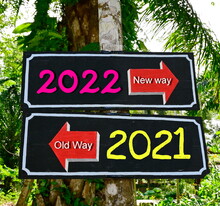 Rectangular Wooden Sign There Are Red Arrows Pointing In Different Directions And Write "new Way 2022" In White, Pink And "old Way 2021" In White And Yellow. Stuck On Tree. Old Year Gone New Year Come