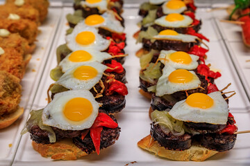 Spanish pintxos of morcilla blood sausage with egg and piquillo peppers on display in a restaurant, San Sebastian Donostia, Basque Country, Spain