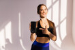 © F8  \ Suport Ukraine - Portrait of a smiling fitness woman pointing finger at blank screen mobile phone isolated over white background