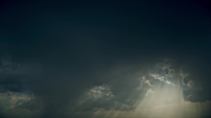 Wall Mural - 4K Sun Rays Shining Through Dark Storm Cloudy Rainy Sky With Fluffy Rain Clouds. Sky Natural Background. Weather Forecast Concept
