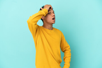 Young African American man isolated on blue background doing surprise gesture while looking to the side