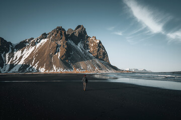 Wall Mural - young man tourist standing at beach during sunset runrise and gorgeous reflection of vestrahorn moun